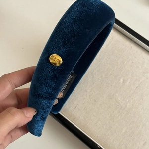 Detail of blue velvet headband with gold metal button and handmade woven label
