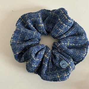 Detail of blue tweed scrunchie with textured fabric and light blue button decoration