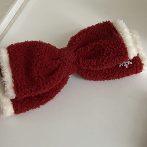 Macro view of red sherpa fleece bow hair clip with white plush trim and silver snowflake