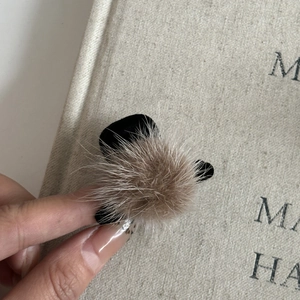 Détail d'une pince à cheveux en fourrure avec pompons marrons et base en velours noir