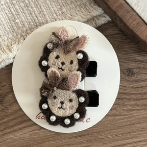 Detail of two handmade bear embroidery hair clips with lace bows and pearl accents