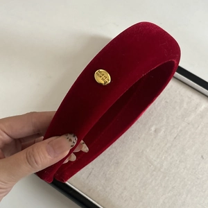 Detail of red velvet padded headband with a golden metal buckle and engraved text