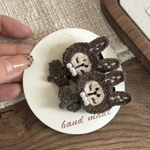 Close-up of handmade brown crochet rabbit hair clips with small pearl decorations