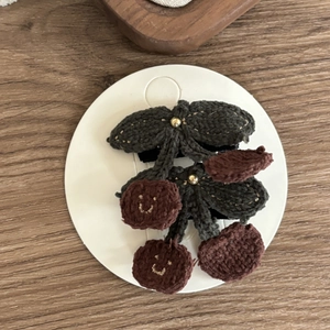 Detail of handmade crochet cherry hair clips with cute smiles and golden beads