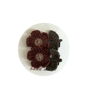 Handmade crochet hair clip featuring dark red flowers and green leaves on a white card