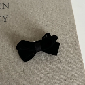 Detailed macro view of a vintage black velvet bow hair clip on a textured linen background