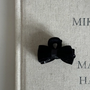 Detail of a small black velvet bow hair claw clip with elegant texture and ribbon center