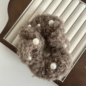Detailansicht eines braunen Plüsch-Haargummis mit weichem Fleece und eleganten Perlen