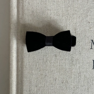 Close-up of black velvet bow hair clip showing soft matte texture and metal fastener