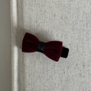 Detail view of red velvet bow hair clip with black ribbon on a linen background