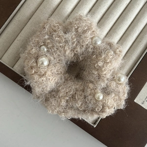 Detail eines beigen Plüsch-Haargummis mit weißen Perlen in einer Schmuckschatulle