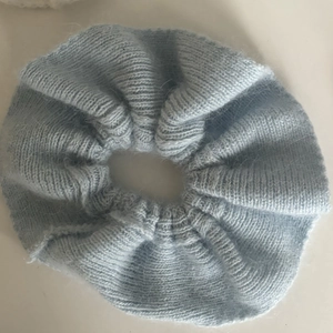 Close-up of light blue knitted scrunchie showing soft mohair texture and ribbed pattern