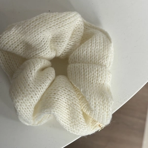 Detaillierte Ansicht des cremeweißen Strick-Scrunchies mit weicher Wollstruktur und Muster
