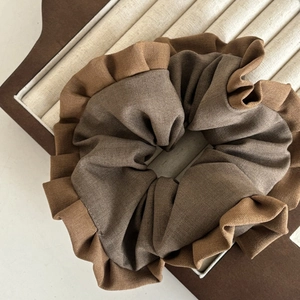 Close-up of two-tone pleated scrunchie in coffee and caramel brown fabric on a tray