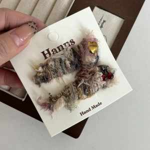 Détail de la pince à cheveux en tricot arc-en-ciel avec cerise et breloque dorée