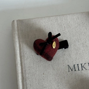 Detail of red plaid heart hair clip with black velvet bow and golden LOVE metal tag