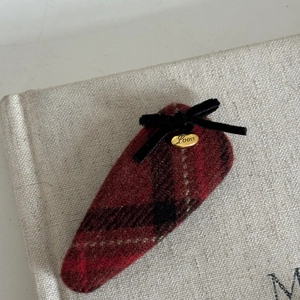 Close-up of red plaid hair clip with black velvet bow and golden Love metal tag
