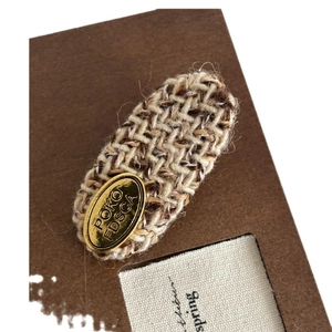 French wool hair clip with woven plaid pattern and gold oval metal brand label