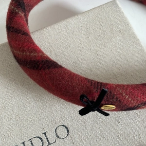 Red plaid headband with black ribbon bow and golden Love tag in a vintage winter style