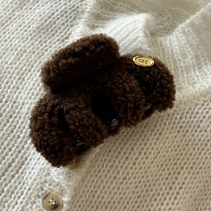 Plush lamb wool hair claw clip in dark brown with a gold metal accent on knit background