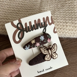 Detail of floral and embroidered butterfly hair clips on a handmade display card