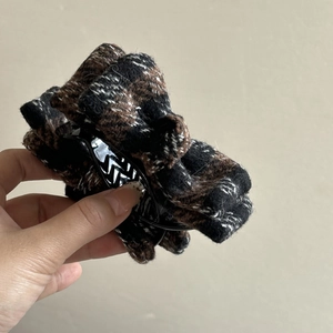 Close-up of a large brown plaid tweed bow hair claw clip with a thick woven texture
