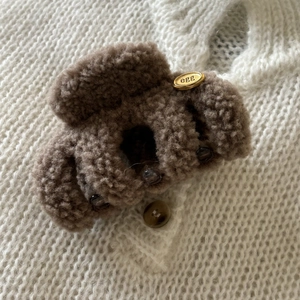 Detail of soft brown faux fur hair claw clip with golden egg tag on knit fabric