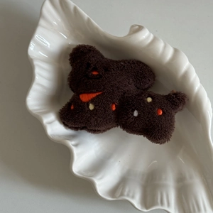 Vue détaillée de la pince à cheveux chiot en peluche marron avec broderie sur un plateau