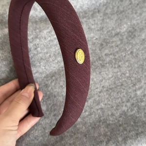 French burgundy fabric headband with golden metal logo plate for elegant hair styling