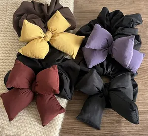 Detailed view of padded bow scrunchies in yellow, purple, burgundy, and black fabric