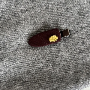 French style burgundy fabric hair clip with a gold metal plate on a textured background
