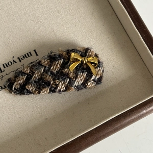 Detail of vintage brown houndstooth hair clip with a small gold bow metal accessory