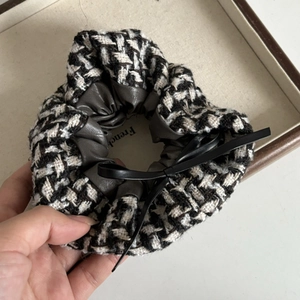 Close-up of retro houndstooth hair scrunchie with a black leather bow detail
