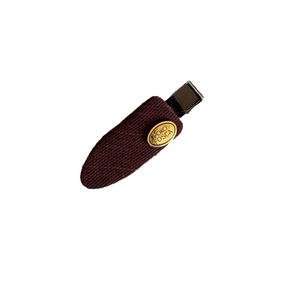 French style burgundy fabric hair clip with a gold oval metal brand logo on white background