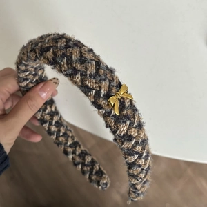 Close-up of thick tweed headband with brown pattern and gold butterfly pendant