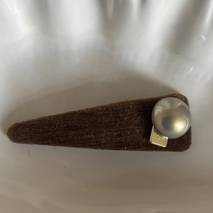 Detail of vintage caramel pearl hair clip featuring brown velvet finish and Luck engraving