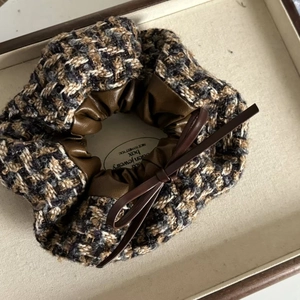 Vintage houndstooth scrunchie with brown leather bow accent on a jewelry tray
