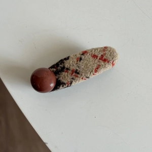 Detail of red and black plaid fabric hair clip with a dark brown resin bead accessory