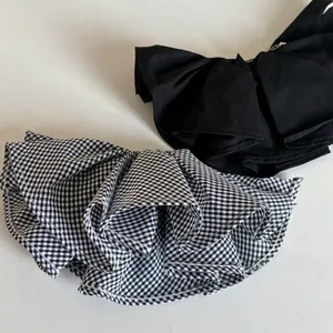 Detailed view of large black and gingham double-layered bow hair clips with textured fabric
