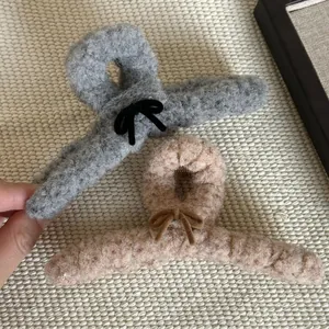 Détail de pinces à cheveux en peluche gris et beige avec nœuds et texture douce