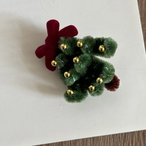 Détail d'une pince à cheveux sapin de Noël en chenille avec nœud rouge et perles dorées