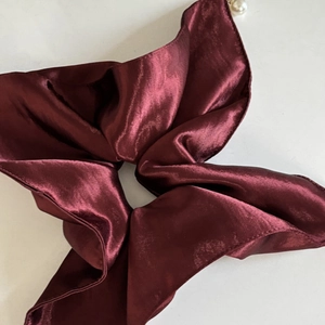 Detailed macro view of wine red satin hair scrunchie with elegant white pearl detail