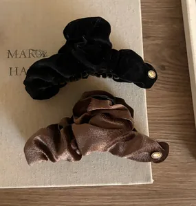 Detail of velvet bow hair claws in black and brown with vintage gold buttons on a book