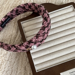 Detail of tweed headband texture featuring pink woven fabric and white pearl ornament