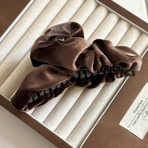 Detail view of large brown velvet hair claw clip with golden metal JOY tag accent