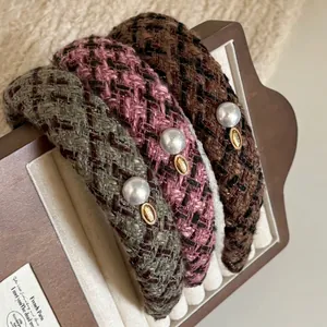 Three vintage plaid tweed headbands with pearls and gold labels on a display stand