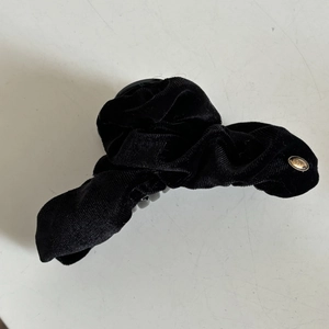 Detail view of large black velvet hair claw clip with gold LOVE oval metal emblem decoration