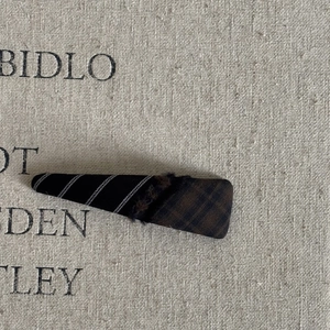 Detail of plaid fringe patchwork hair clip with fabric texture on linen background