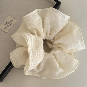 Detail of cream beige seersucker scrunchie with layered texture and ruffled fabric design