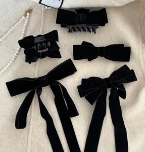 Detail of vintage black velvet bow hair clips and claw clip on a beige knit surface